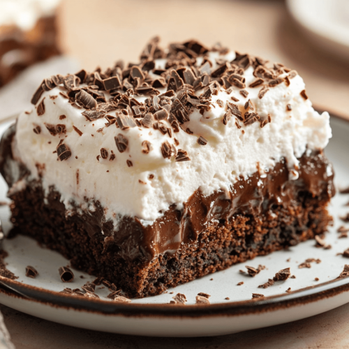 A perfectly plated slice of Death by Chocolate Poke Cake topped with whipped cream and chocolate shavings