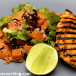 Grilled chipotle chicken with sweet potato quinoa salad and lime wedge on a grey plate.